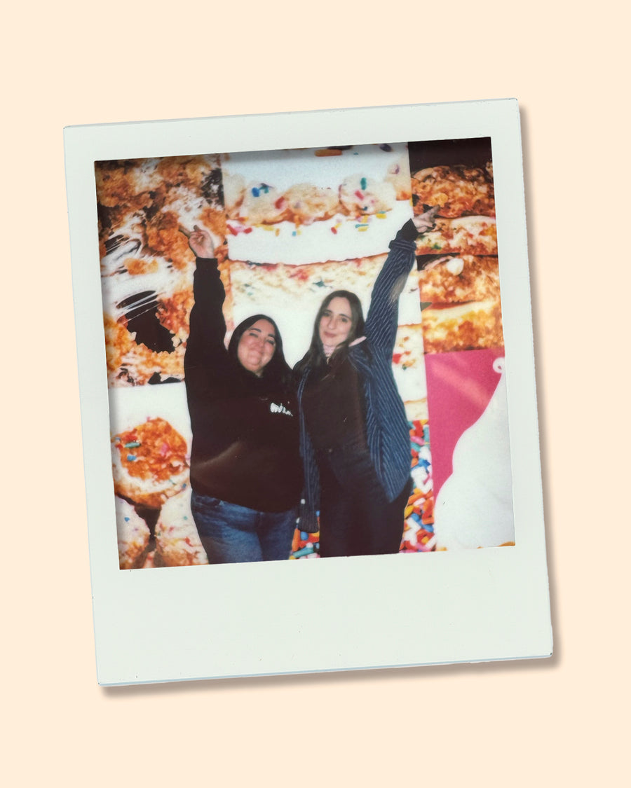Two Milk Bar team members posing in front of a dessert wall